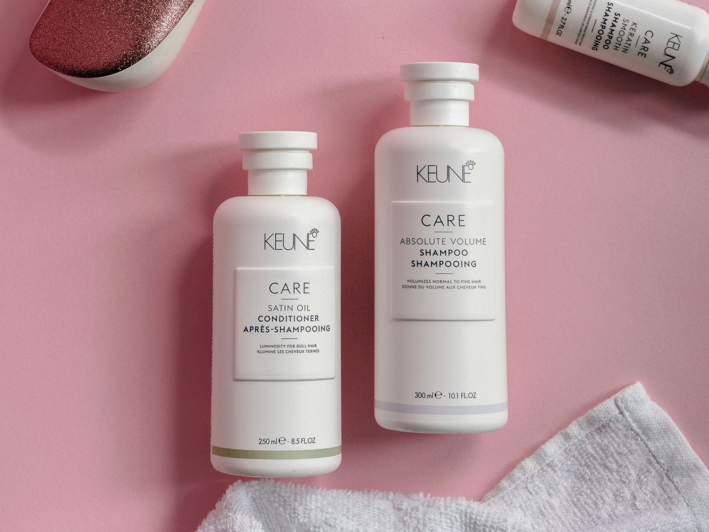 Shampoo and conditioner bottles on a pink surface