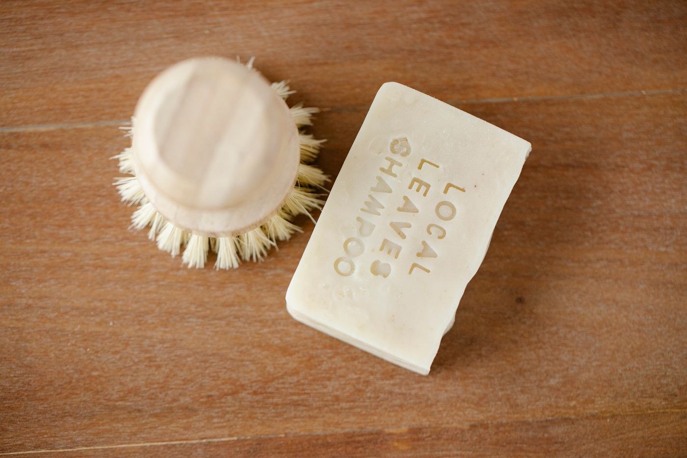 A solid shampoo bar beside a wooden brush