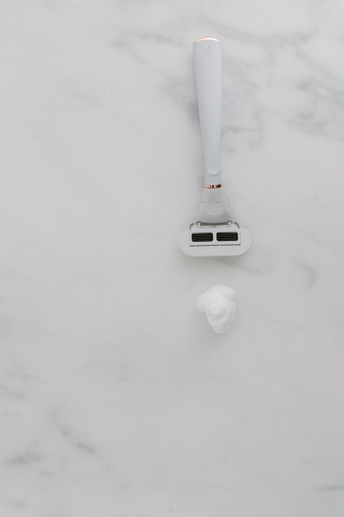 A razor and shaving cream on a marble surface