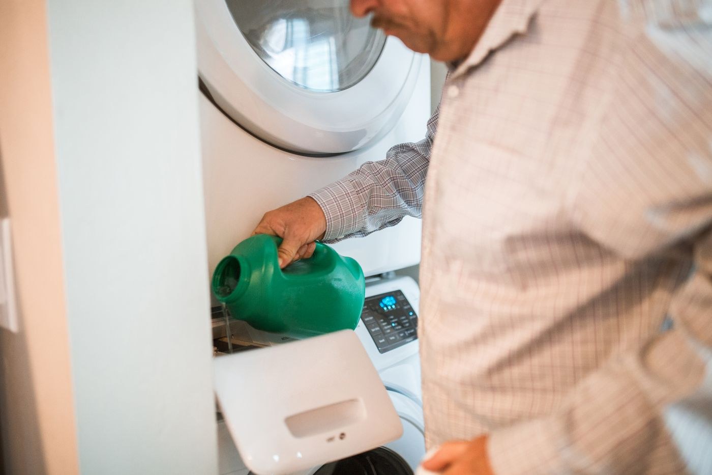 A man adds detergent to a washing machine drawer