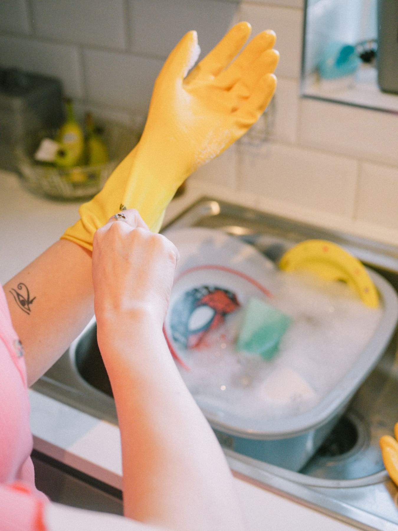 A person puts on rubber gloves at a kitchen sink