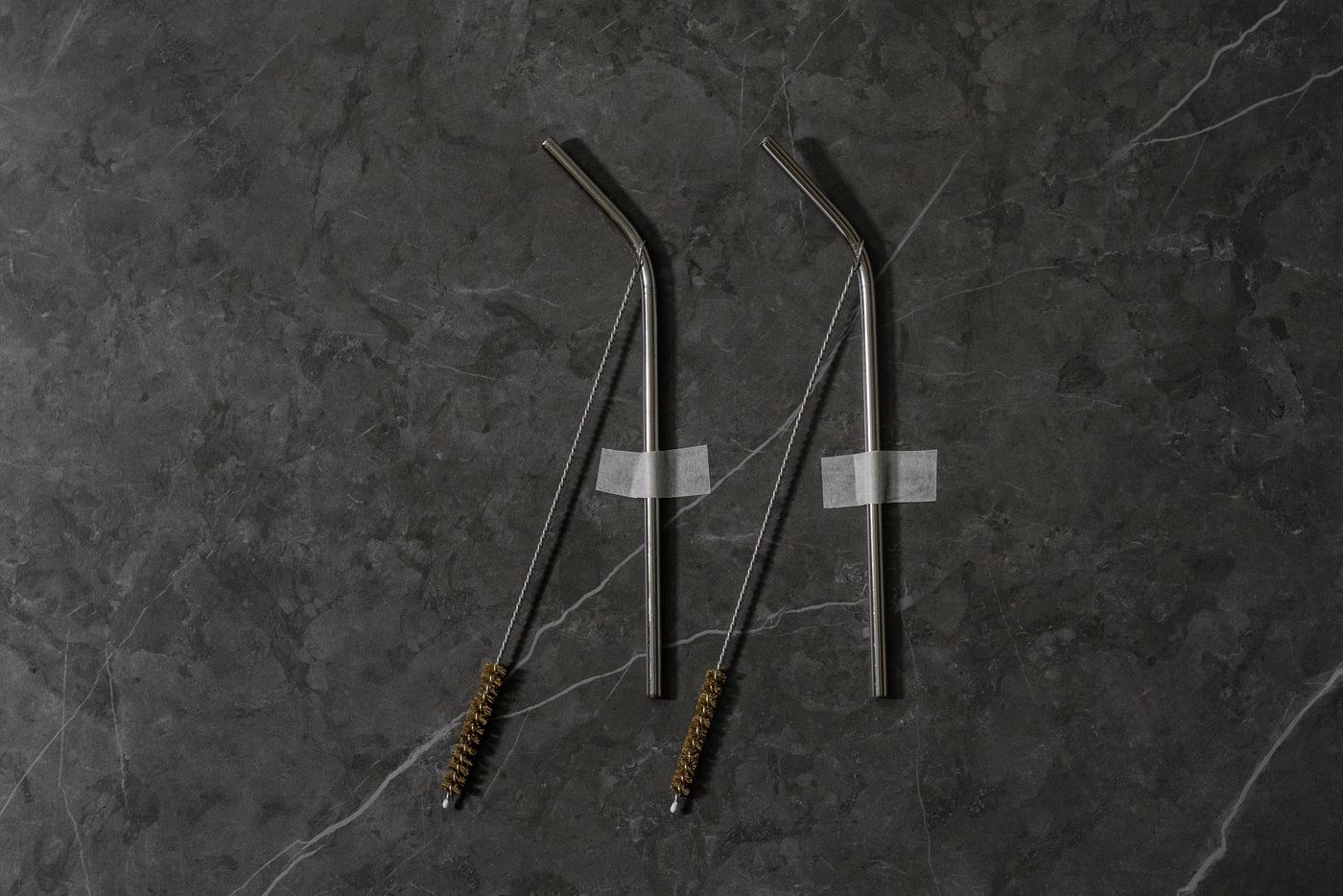 Metal drinking straws beside narrow cleaning brushes