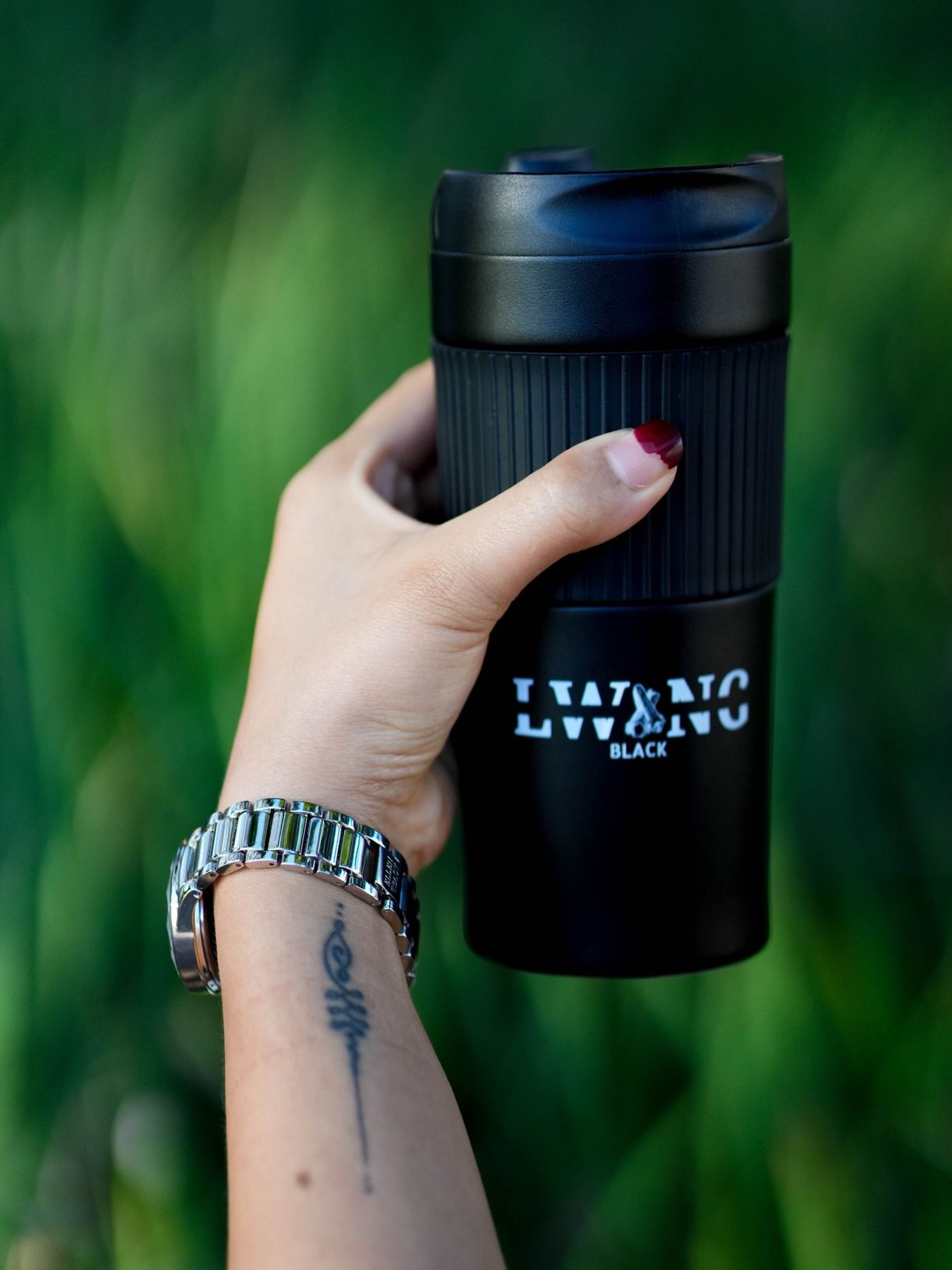 A hand holds a black insulated travel mug