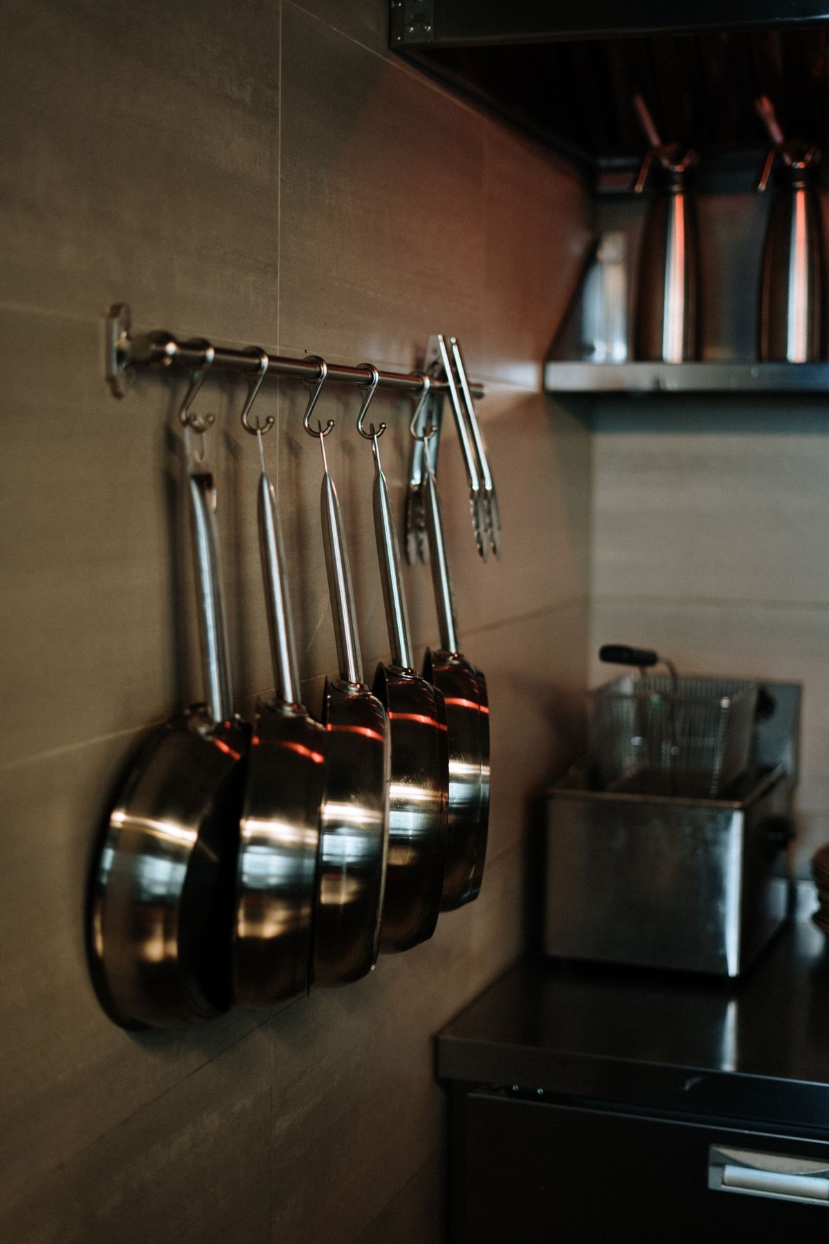 Stainless steel pans hanging above a kitchen sink