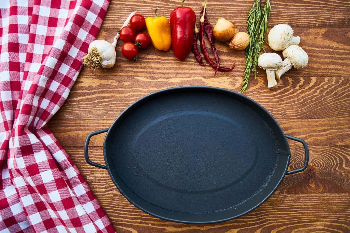 An empty cast iron skillet beside cooking ingredients