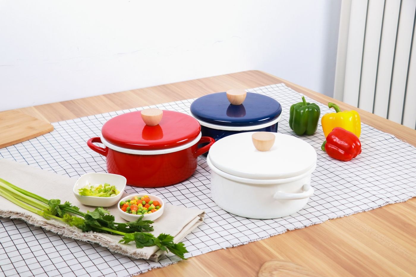 Enamel cooking pots with coloured lids on a table