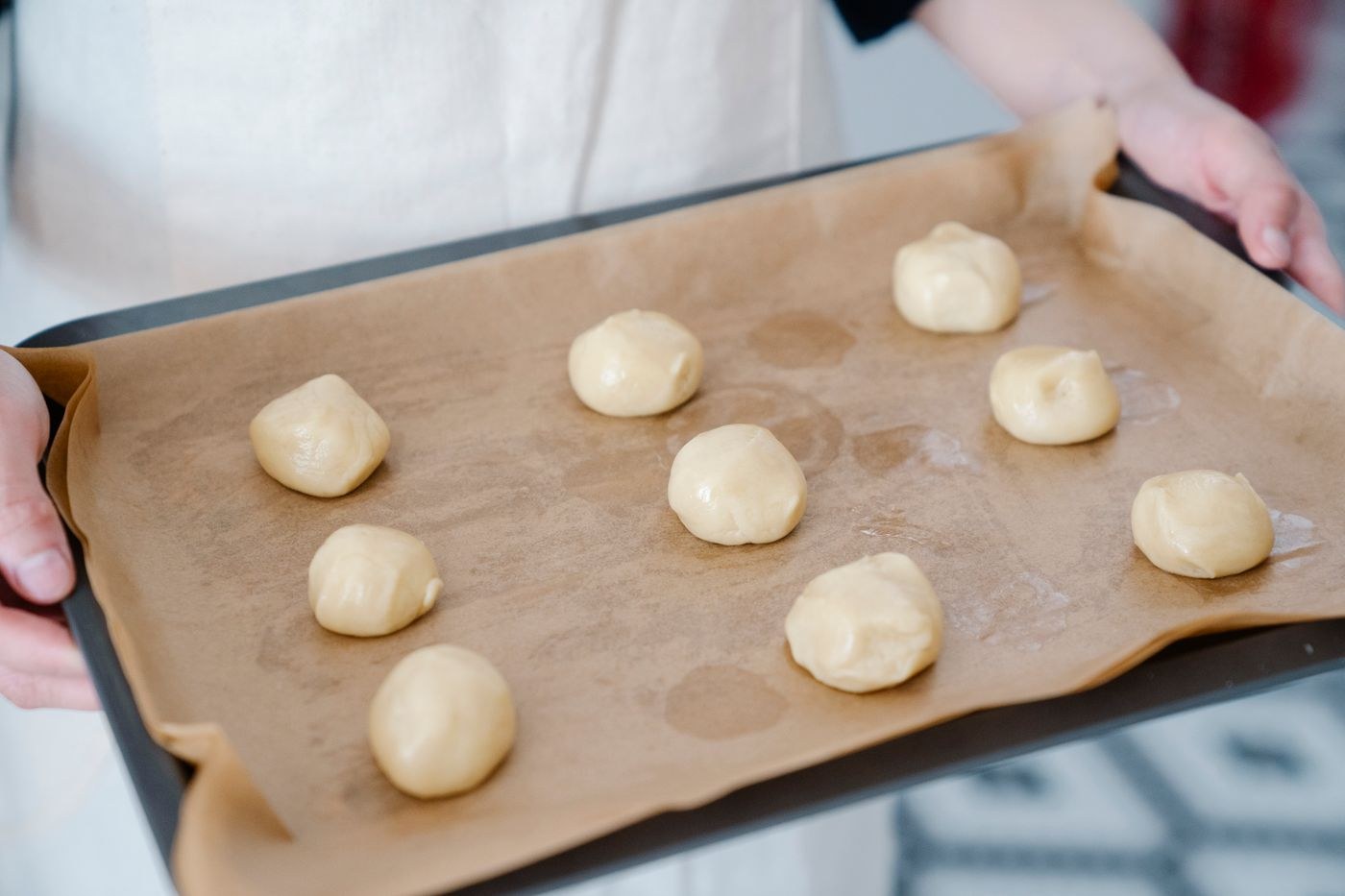 Round dough portions on paper in a baking tray