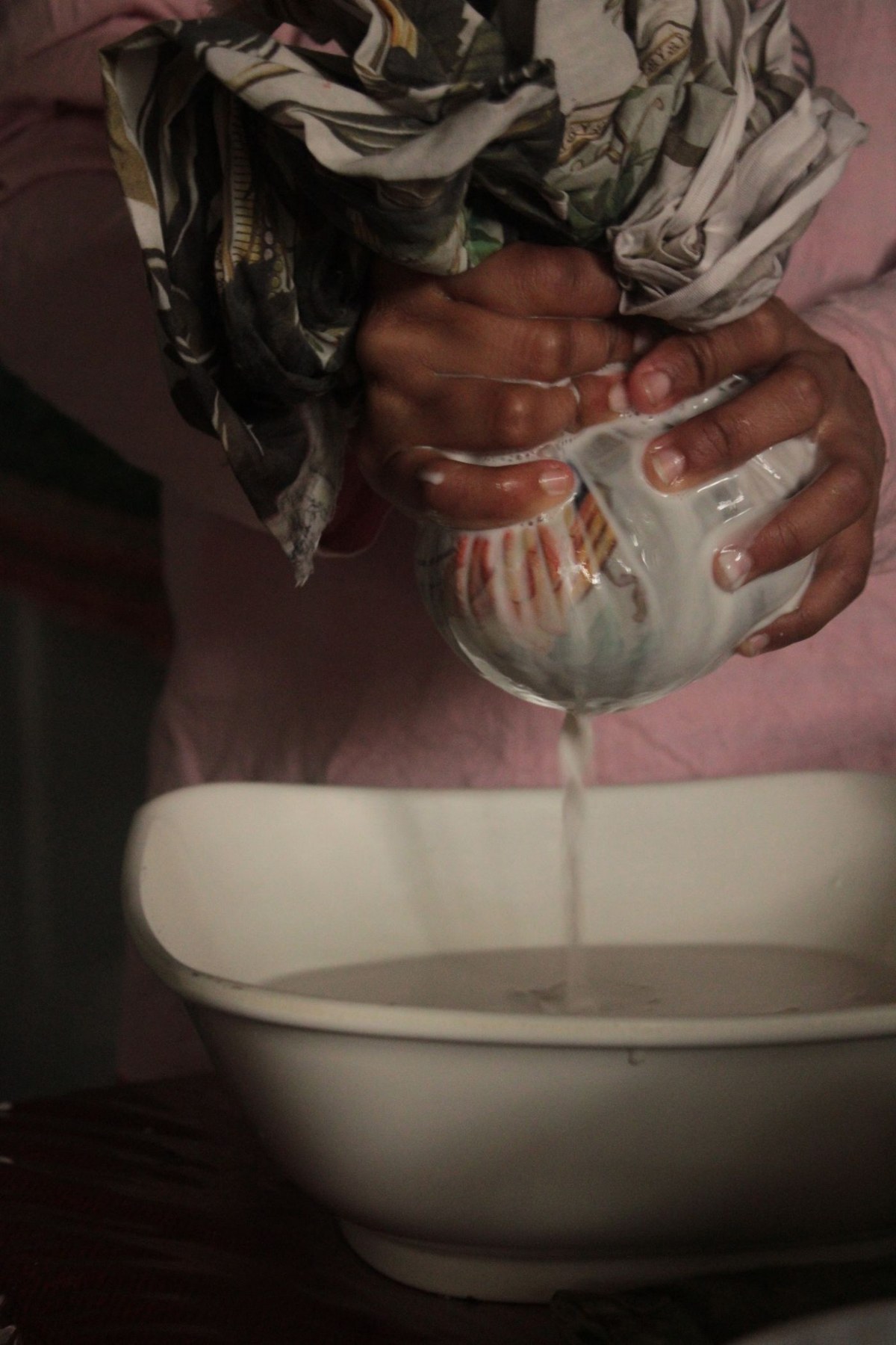Hands wring out a damp cleaning cloth over a bowl