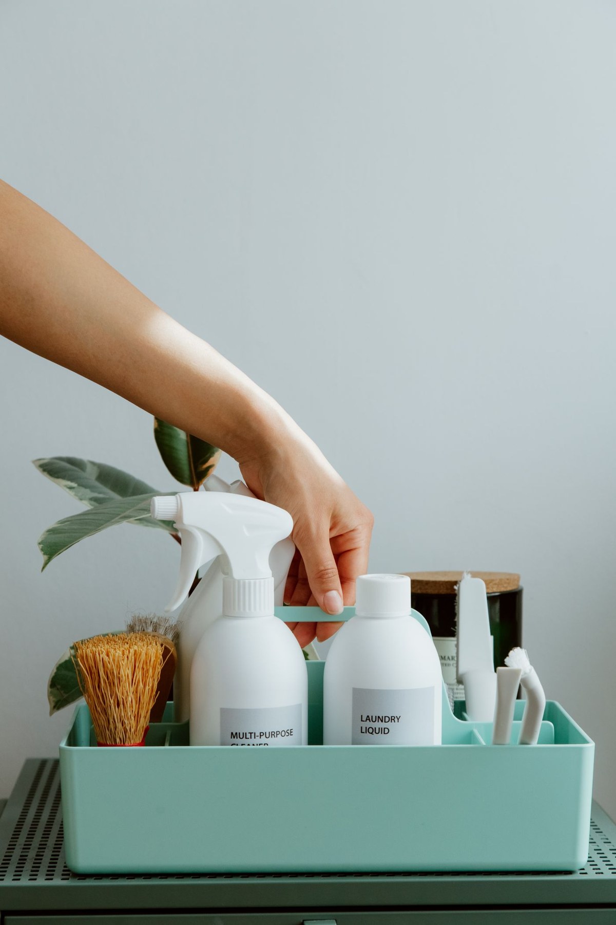 A hand selects a household product from an organised caddy